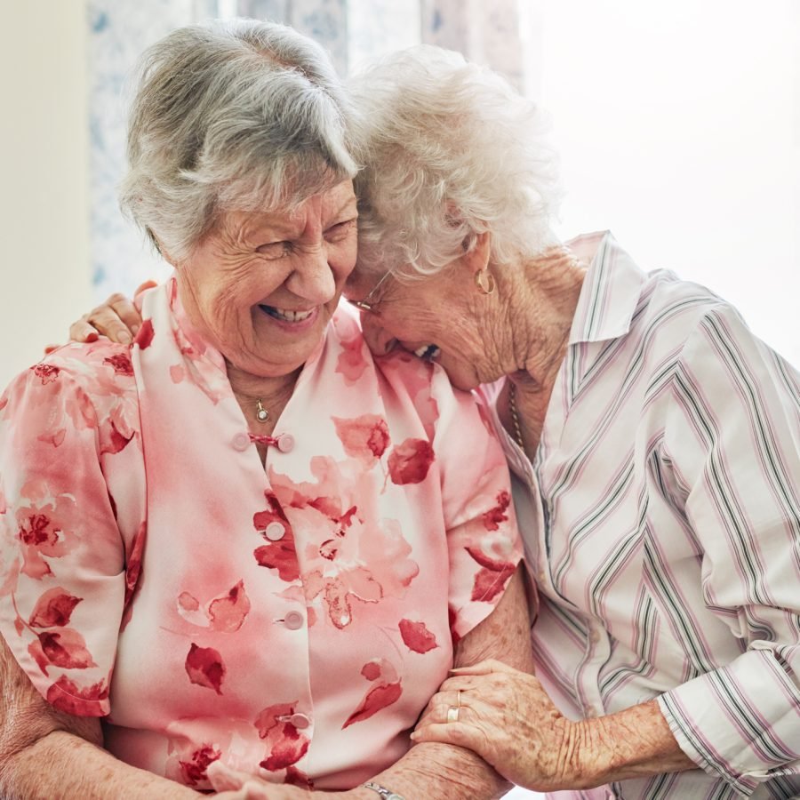 To kvinnelige pensjonister klemmer og ler